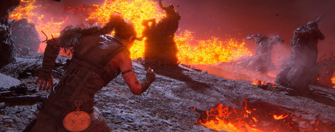 Warrior facing stone monsters in a fiery landscape, Hellblade 2 game action